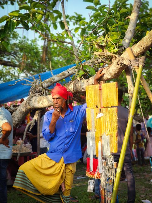 Free A vendor in vibrant attire at an outdoor market, showcasing beads and accessories. Stock Photo