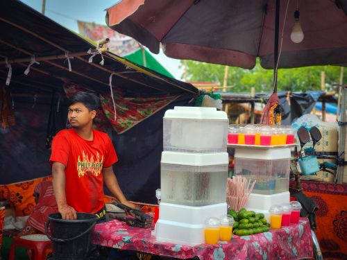 Free A street vendor prepares colorful drinks at an outdoor market, showcasing vibrant tropical juices. Stock Photo