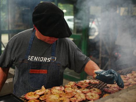 Man grilling traditional Argentinean sausages at an outdoor asado event in Uribelarrea.