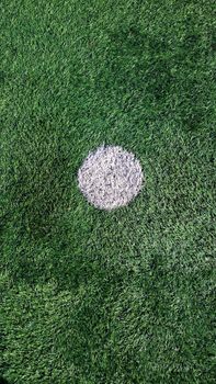 A detailed view of a soccer field's penalty spot on lush green artificial turf.