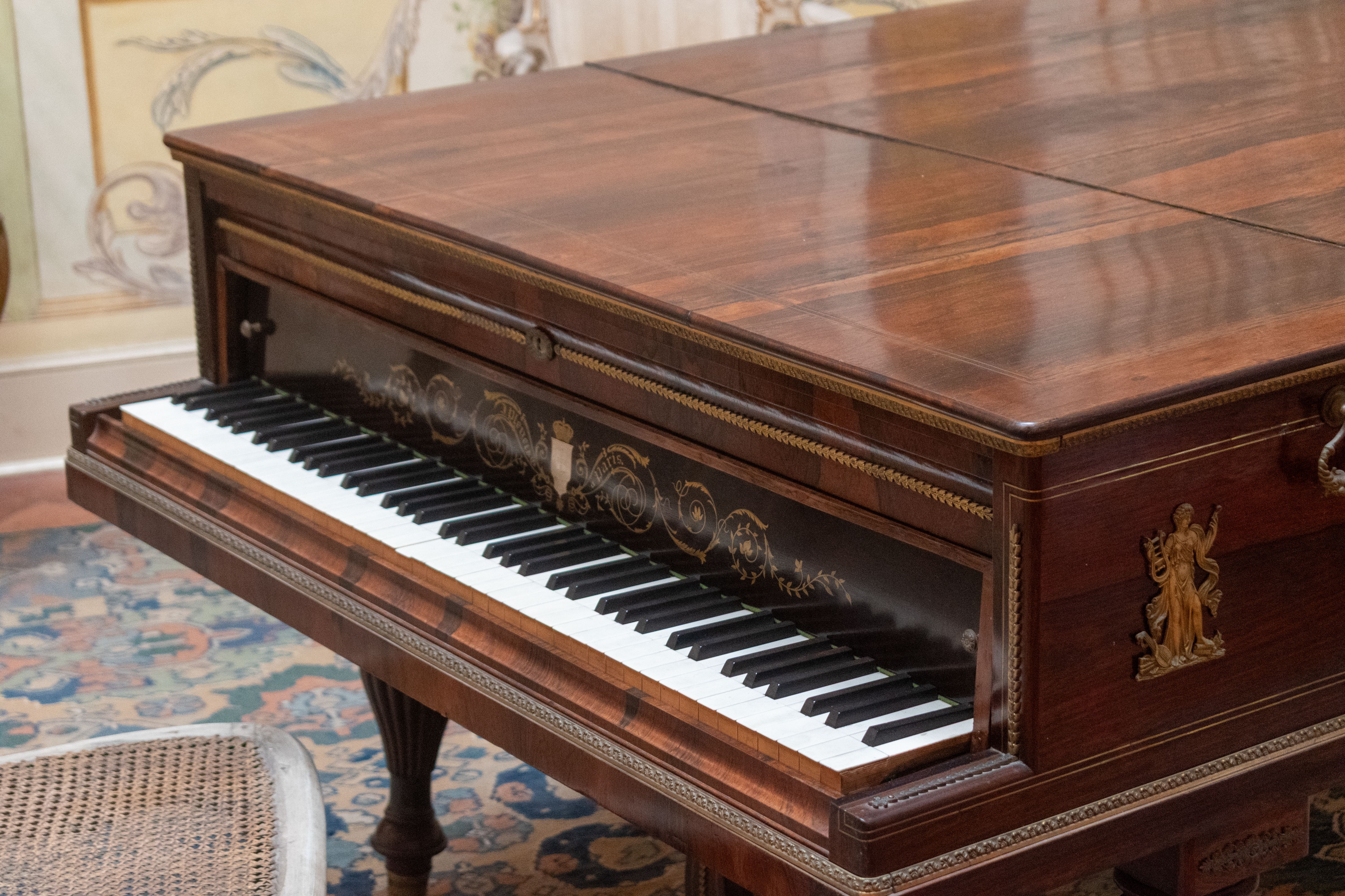 A beautifully crafted antique piano with detailed embellishments in a classic interior setting.