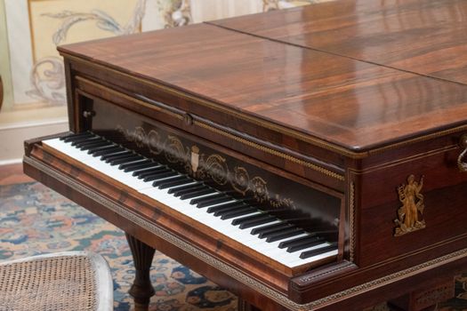 A beautifully crafted antique piano with detailed embellishments in a classic interior setting.