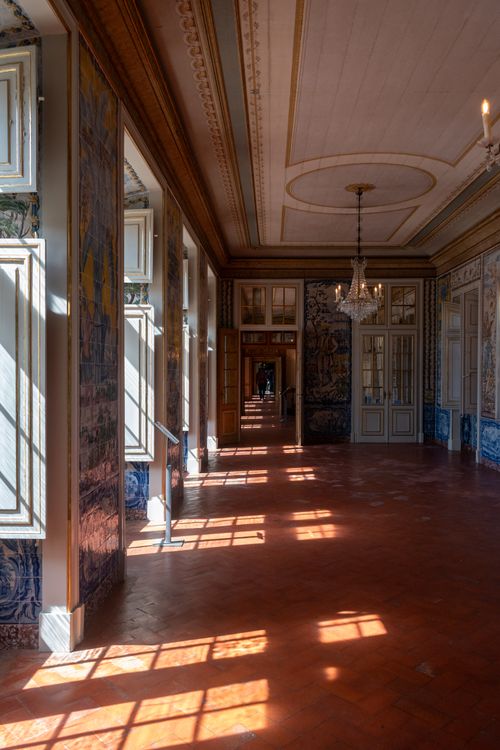 Free A sunlit museum hallway featuring classic architecture with chandeliers, ornate ceilings, and tiled flooring. Stock Photo