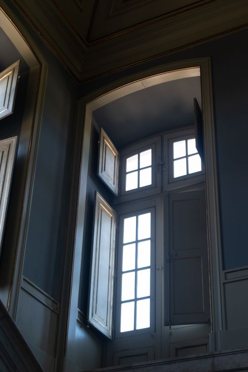 Free Sunlight streams through an elegant arched window, casting soft shadows in a classic interior. Stock Photo