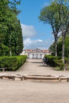 A peaceful garden path leading to a historic building under a blue sky.
