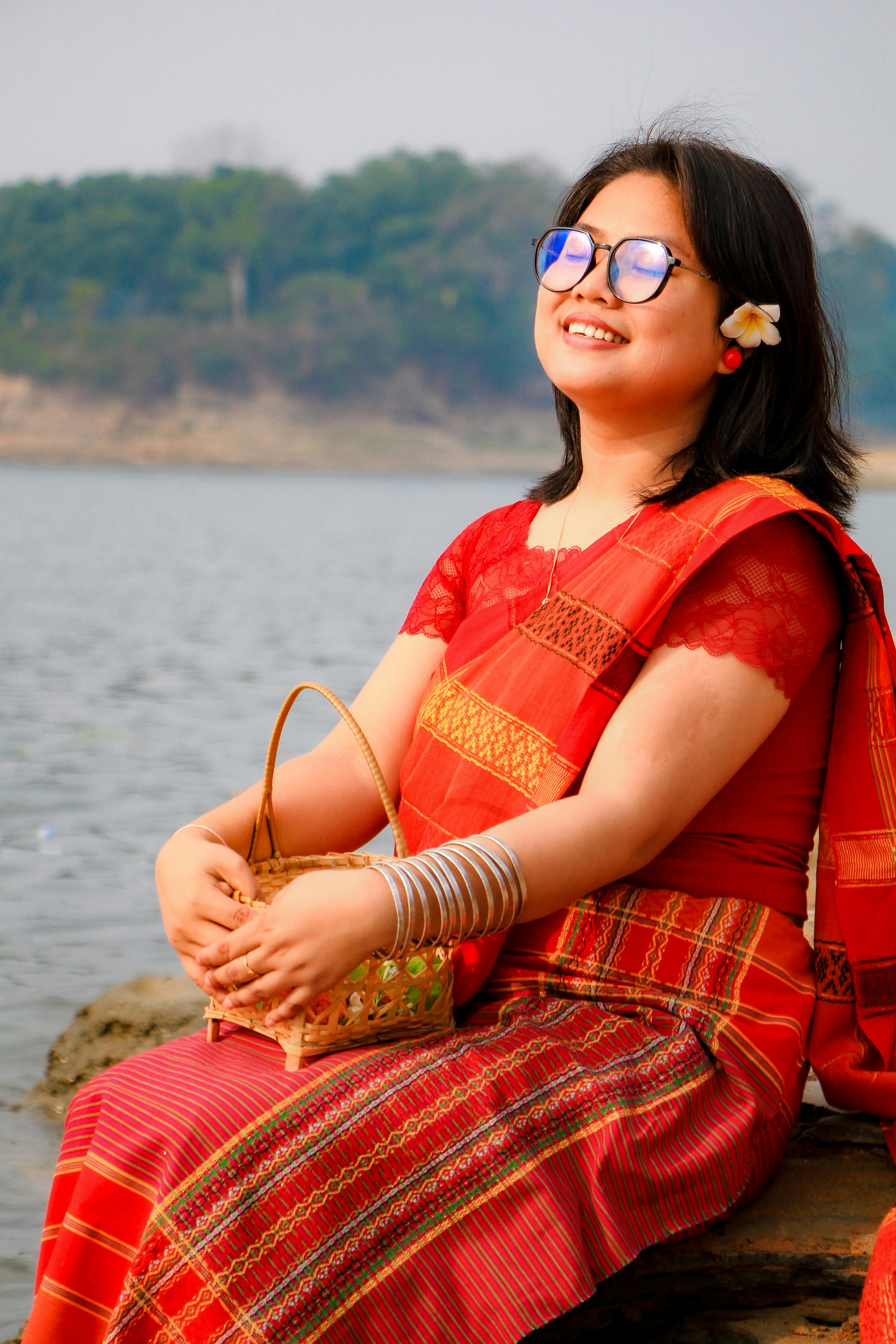 Woman in traditional attire by a river celebrating a cultural festival in Bangladesh.