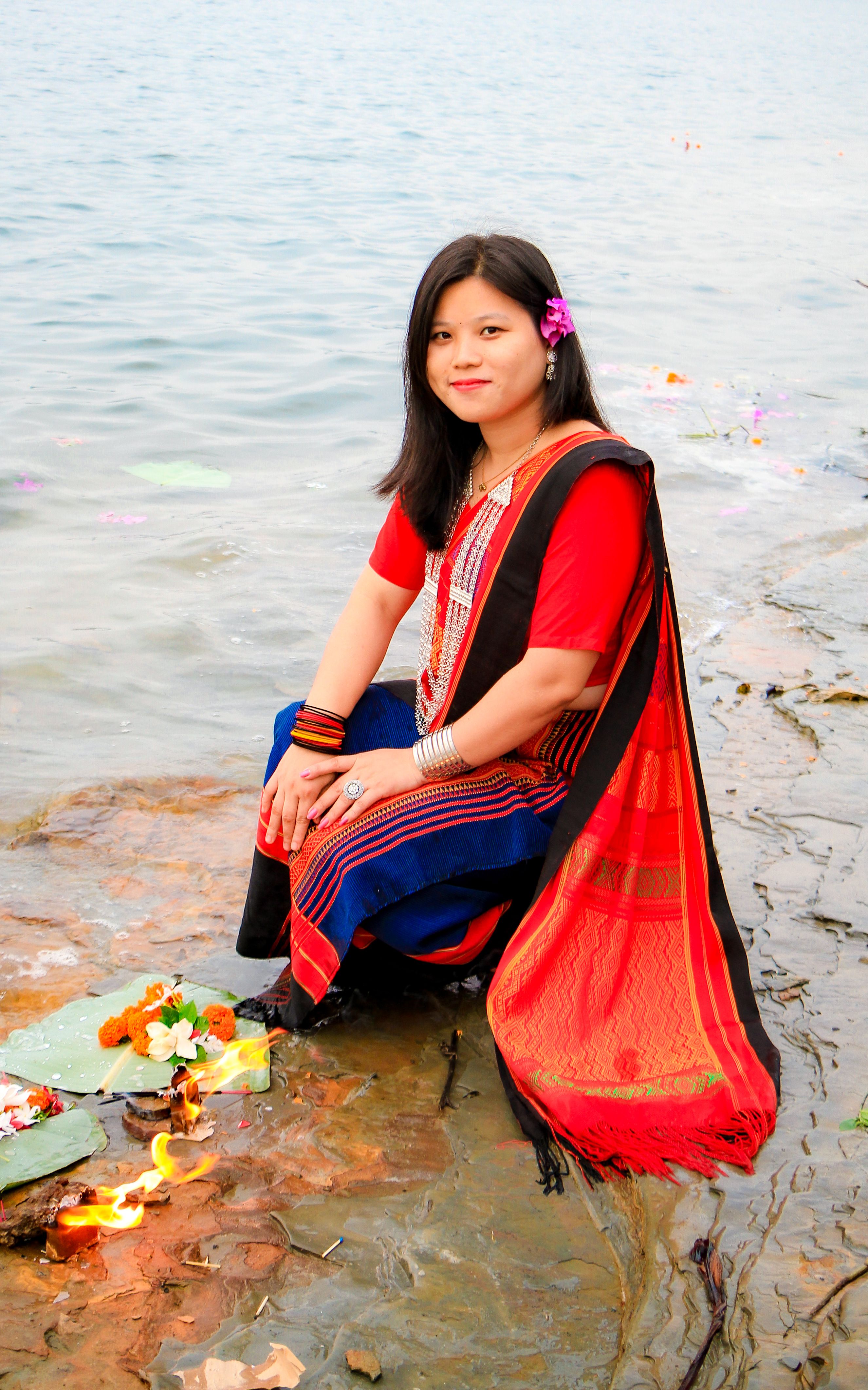 A woman in traditional attire participates in a floral offering ritual by Kaptai Lake in Bangladesh.