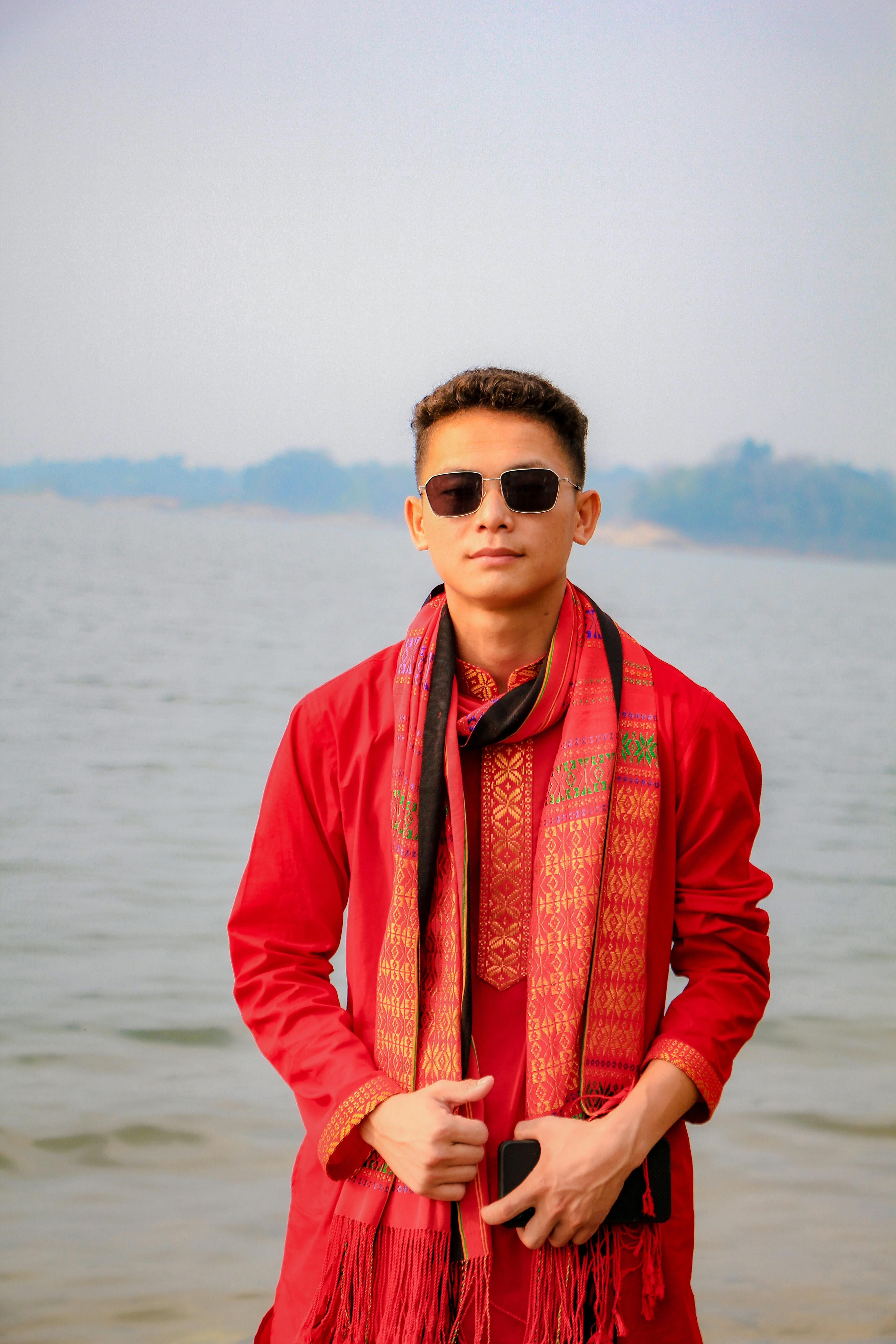 Young man in traditional attire celebrating by the river in Bangladesh.