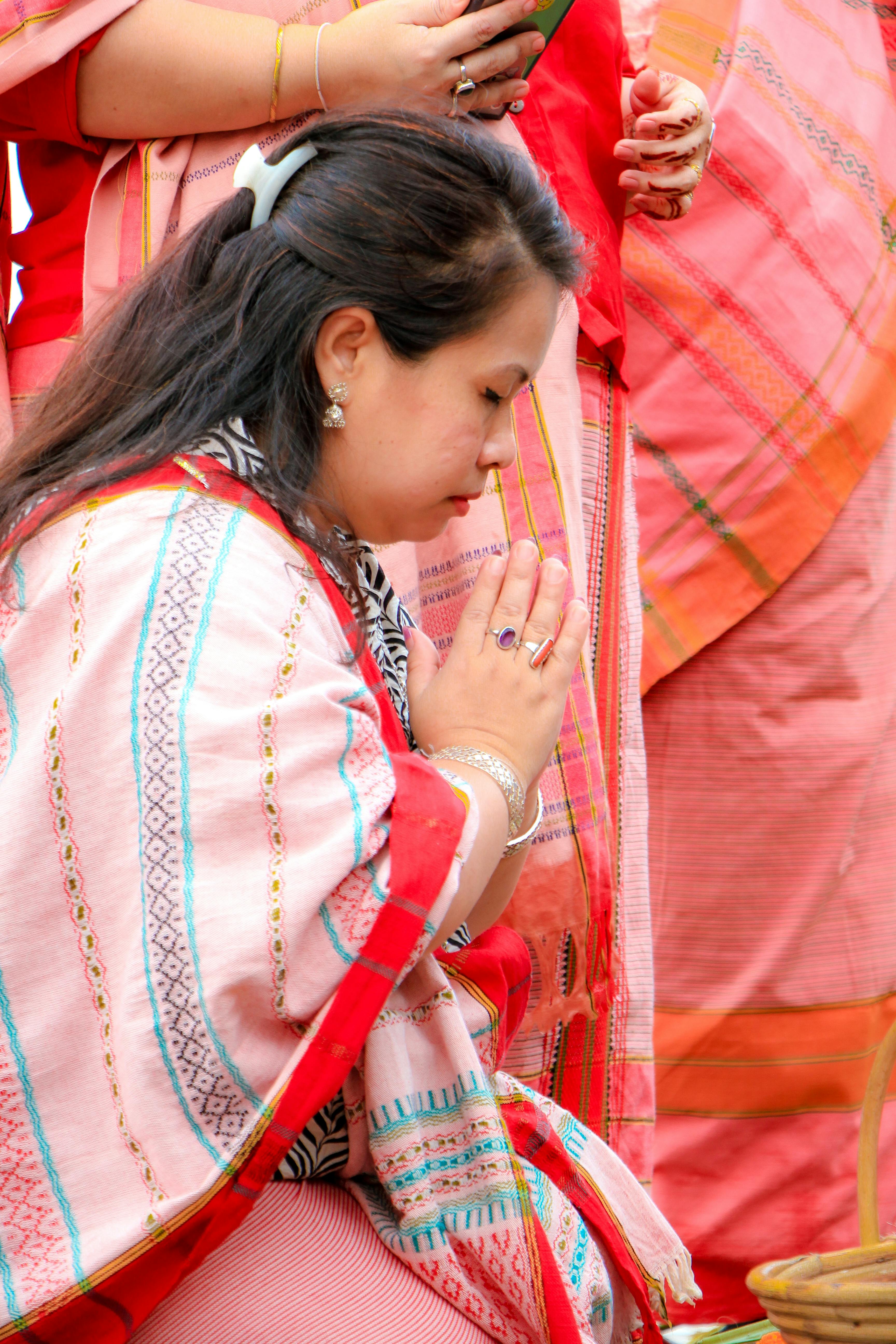 A woman participates in a traditional prayer ritual in Rangamati, showcasing indigenous culture and attire.