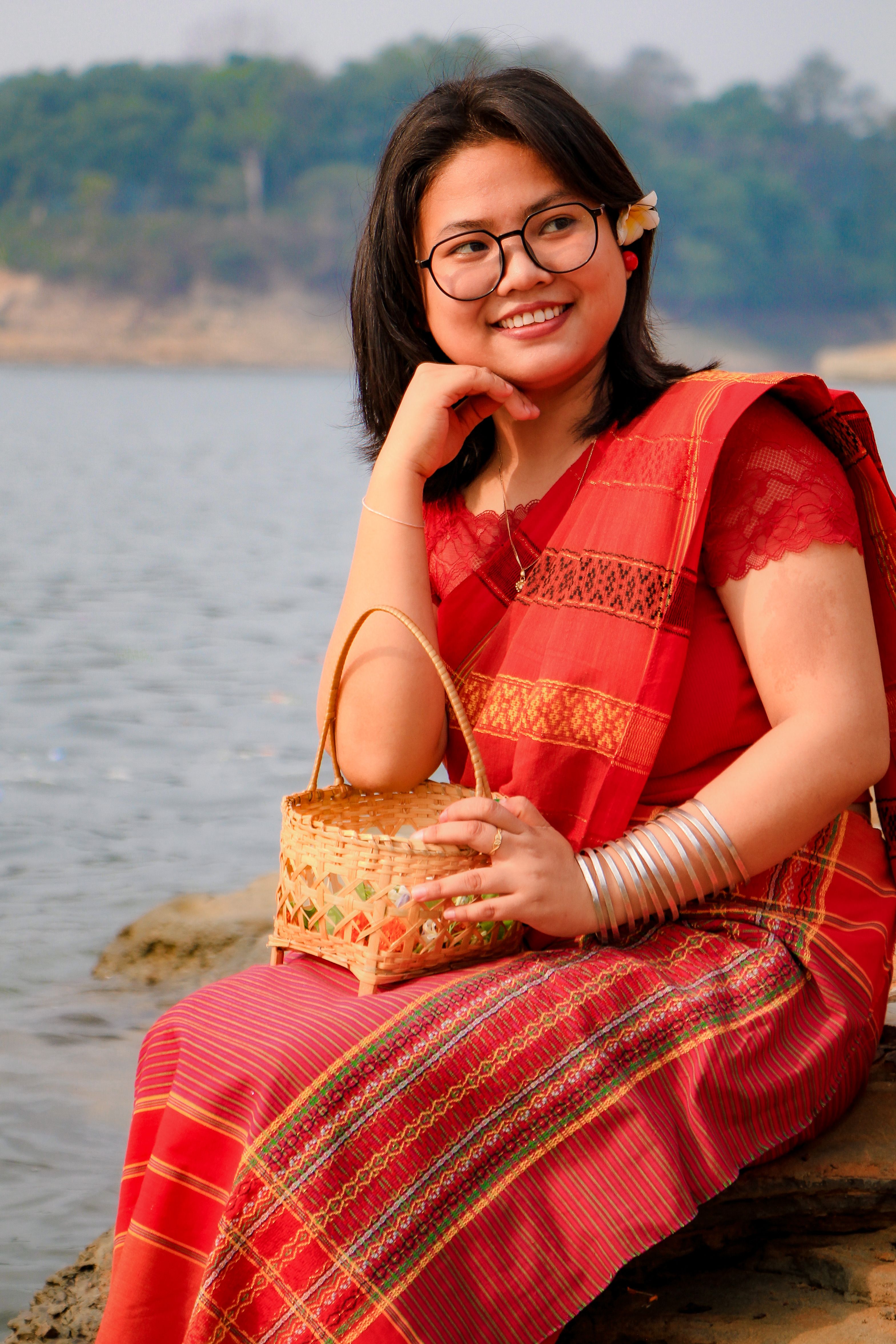 A woman in traditional attire enjoying the Biju Festival by the river in Rangamati.