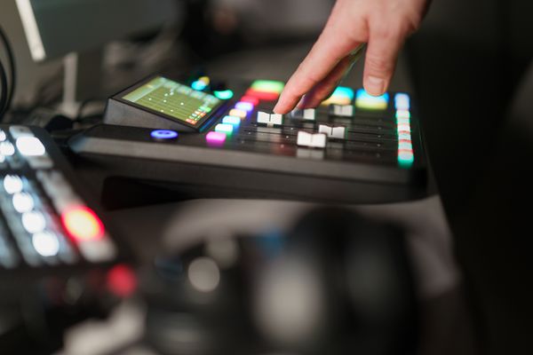 Hand working a lit broadcast control surface — photo by Jakub Zerdzicki on Pexels
