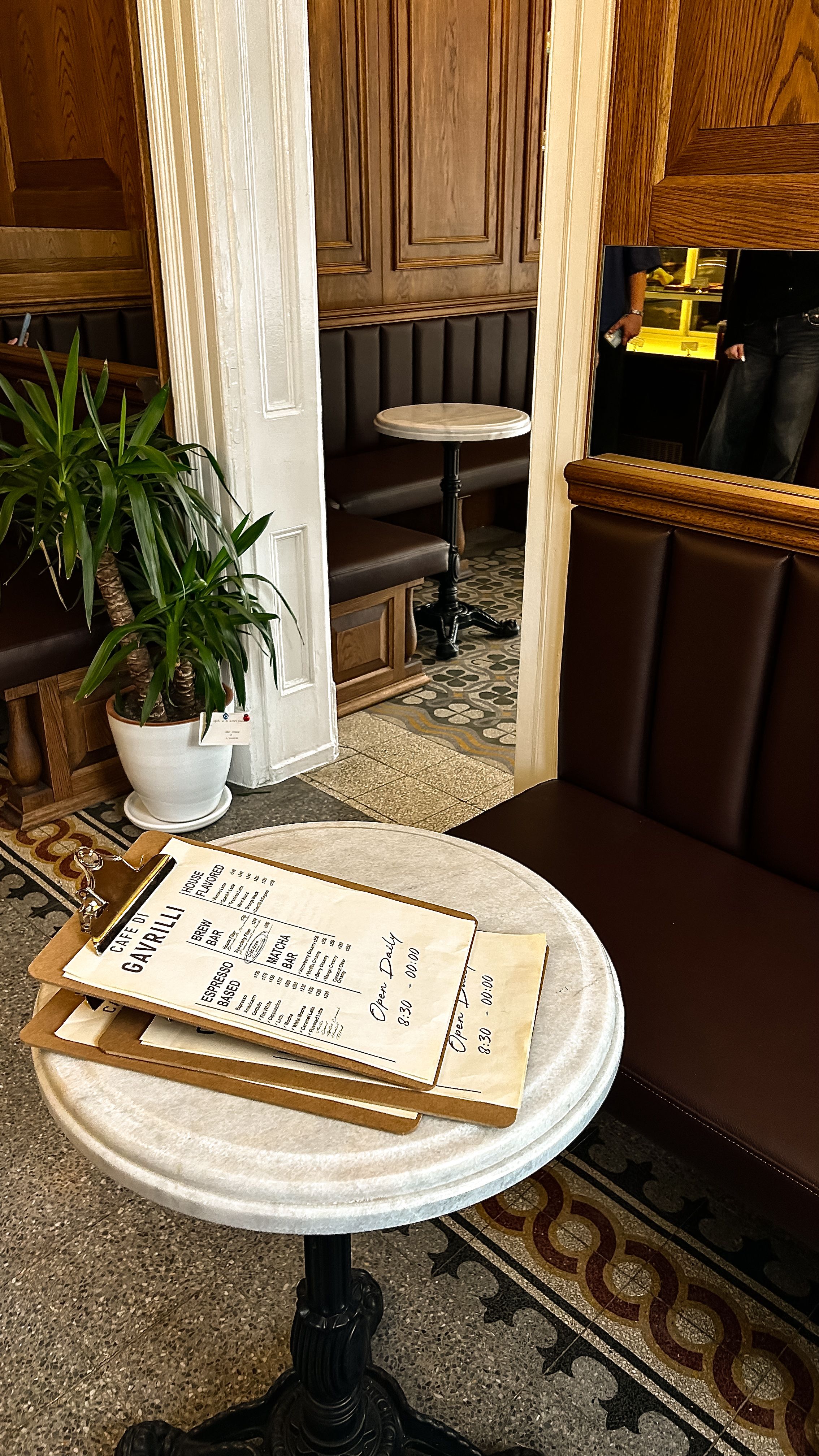 Inviting cafe interior with a menu on a marble table, wooden booths, and decorative flooring.