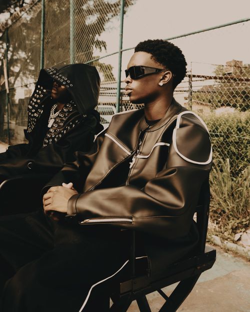 Free Fashionable individuals sitting outdoors, showcasing modern streetwear style. Stock Photo