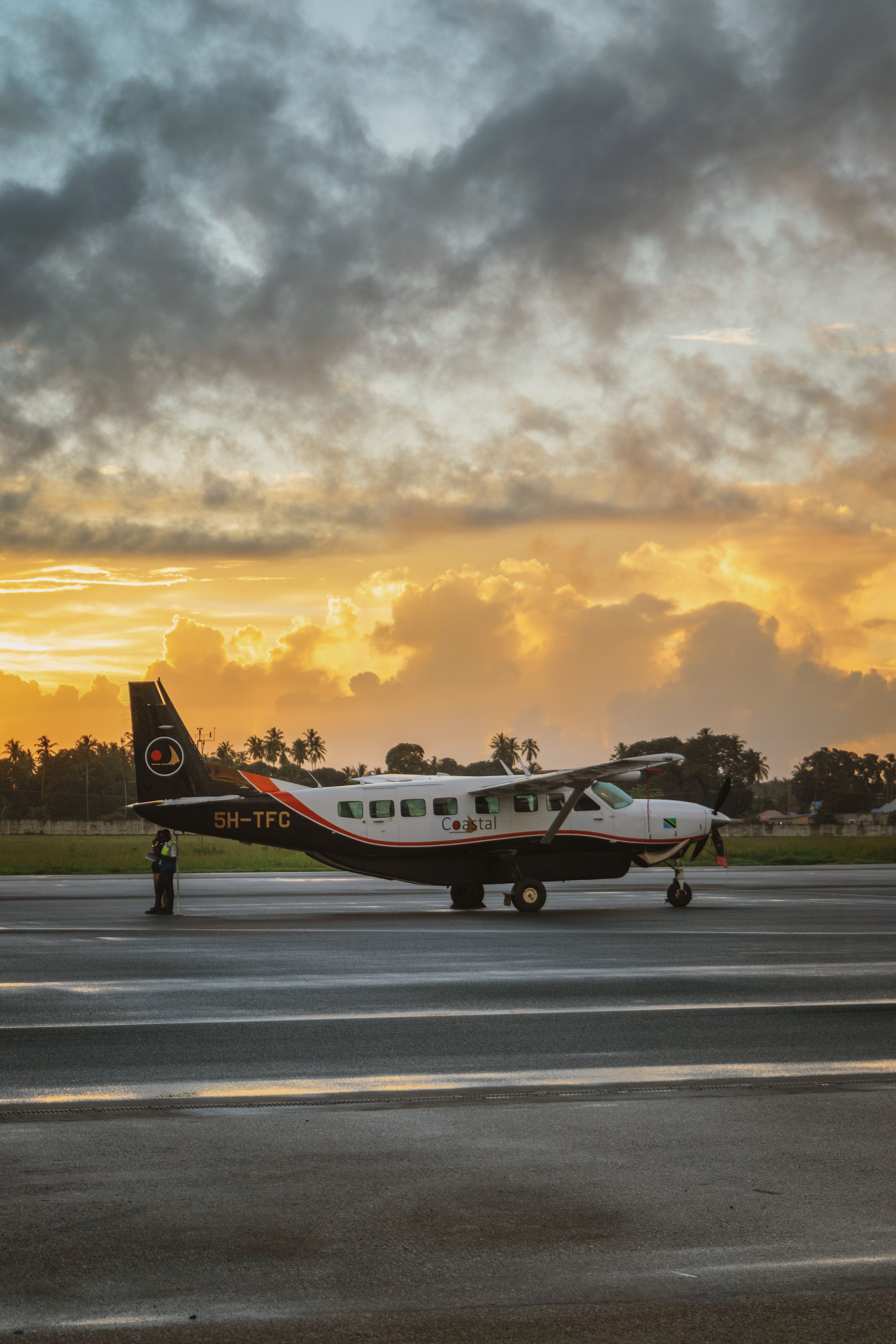 A small aircraft parked at Zanzibar Airport with a stunning sunset sky in the background, capturing travel serenity.