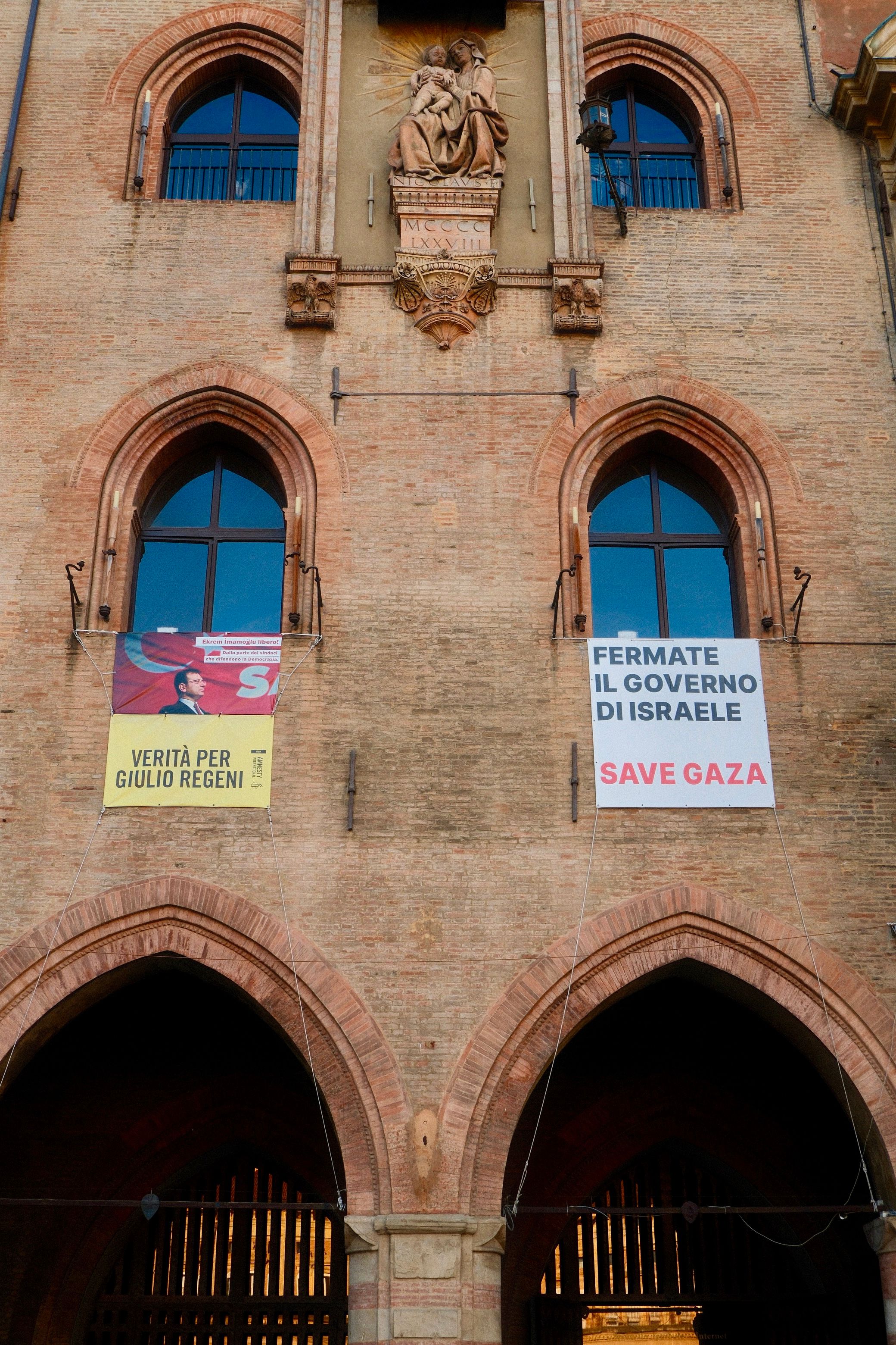 A historic building facade in Bolonya, Italy, displaying political banners.