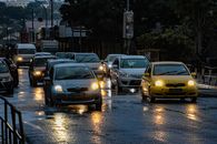 City street traffic during rain shower creating reflections on wet road.