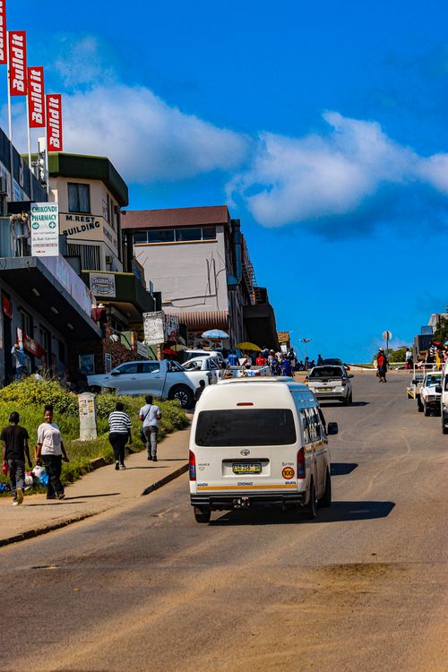 Free Vibrant street in Eswatini featuring people, cars, and local businesses under a clear blue sky. Stock Photo