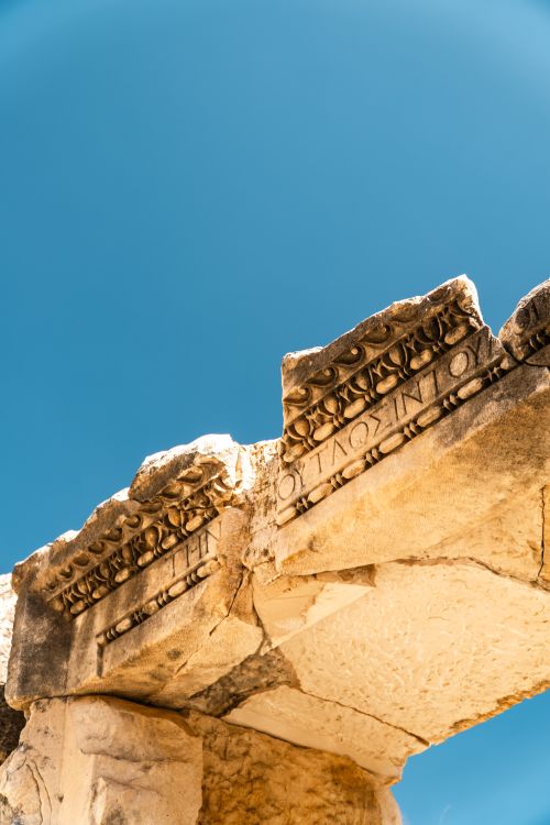 Free Close-up of a detailed ancient stone arch against a vibrant blue sky in Antalya. Stock Photo