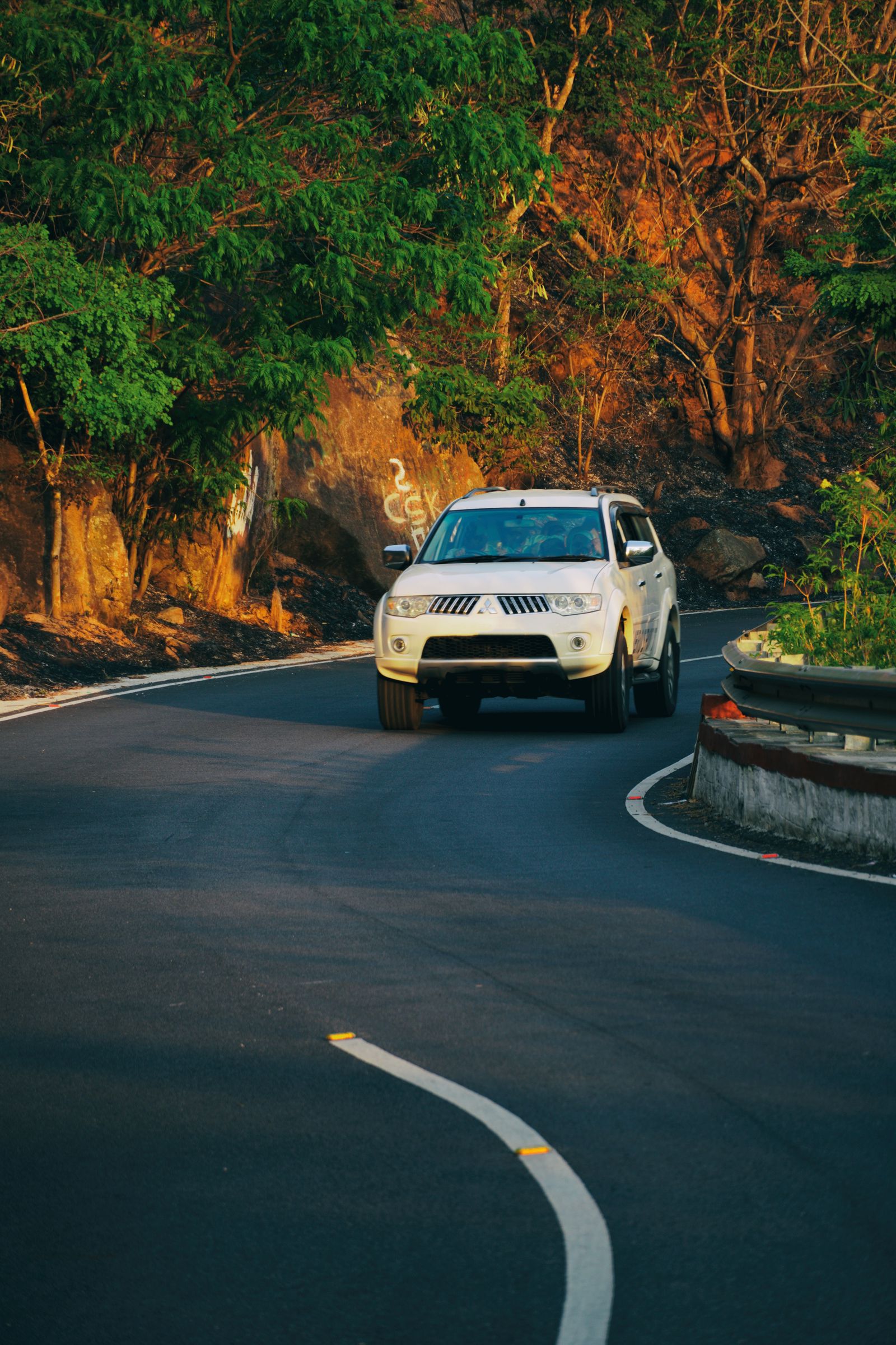 A vehicle on a long winding highway through the hills