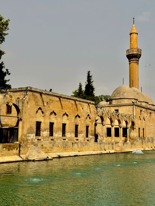 Free Beautiful historic mosque with minaret by a tranquil river in Şanlıurfa, showcasing stunning architecture. Stock Photo