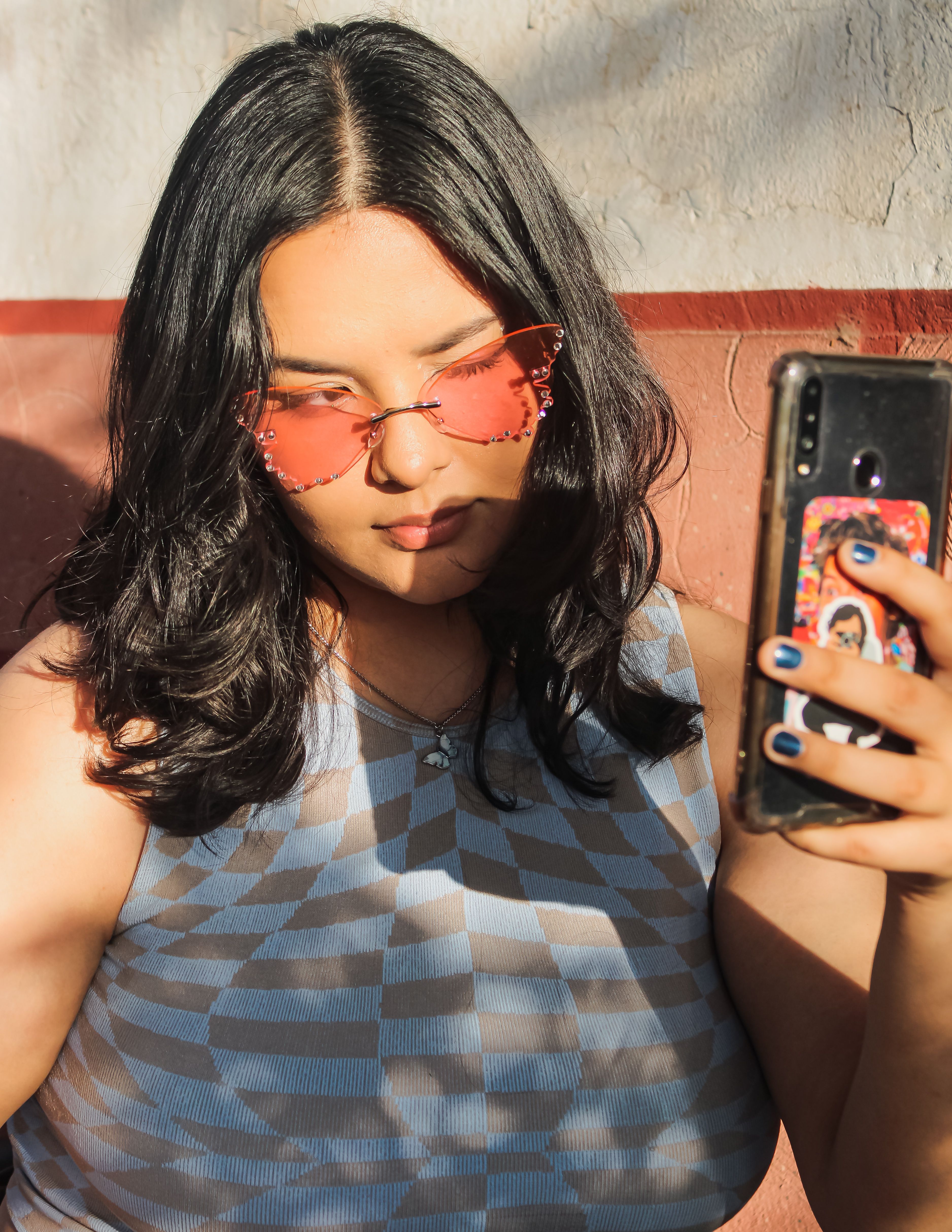 Stylish woman with sunglasses taking a selfie outdoors. Perfect for lifestyle and fashion themes.