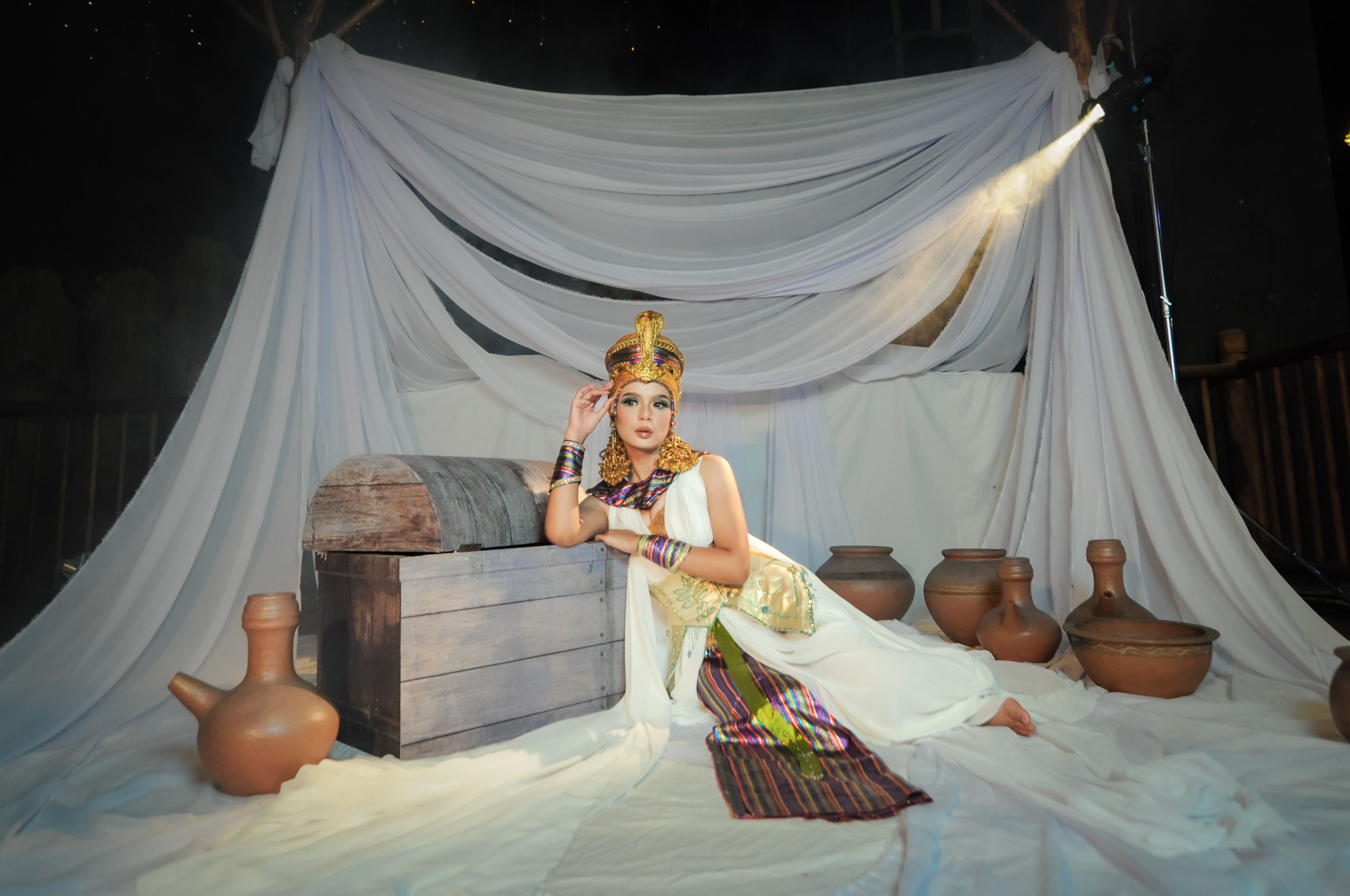 A woman in traditional attire surrounded by pottery in a cultural setting, depicting classic Indonesian heritage.
