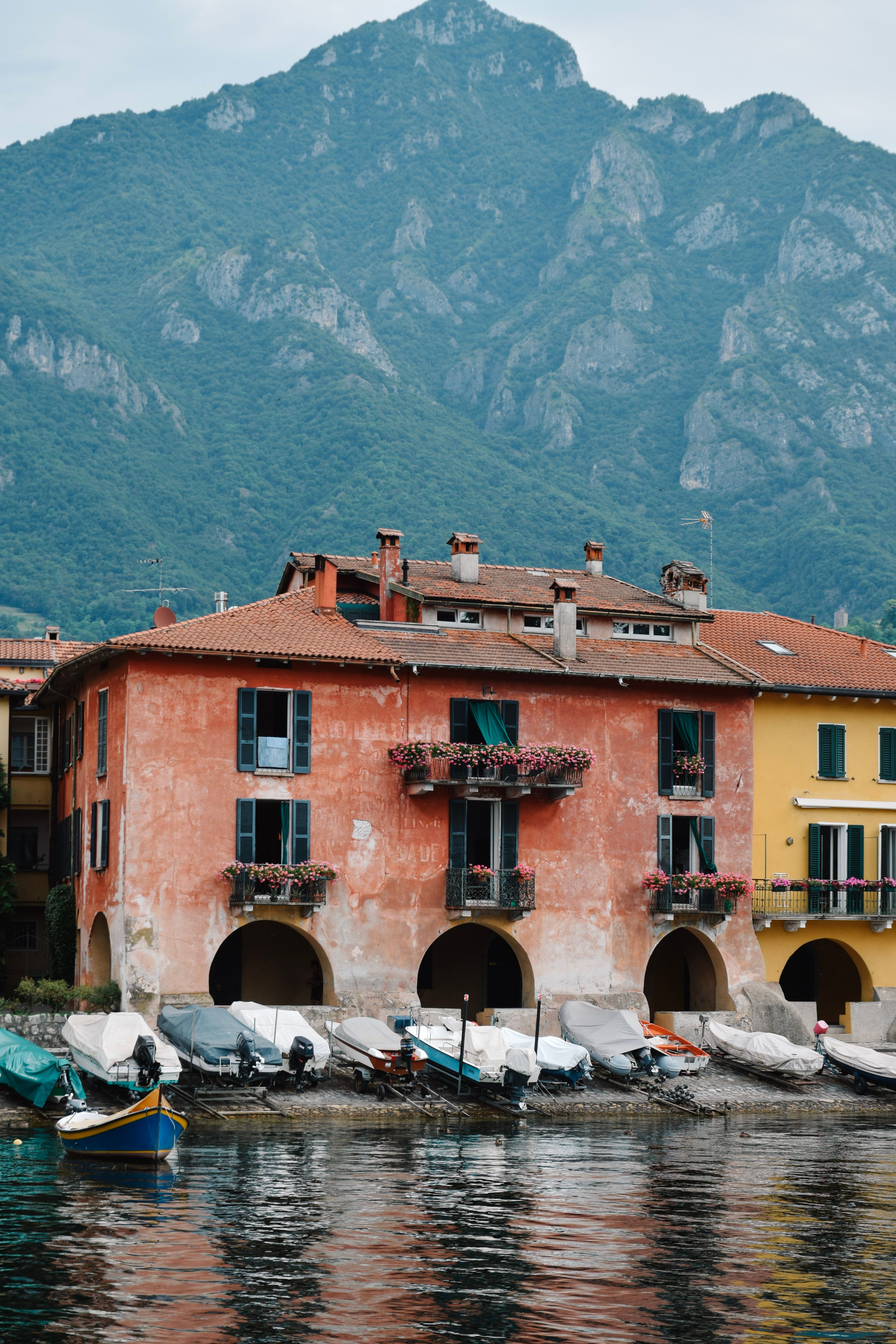 Picturesque view of colorful waterfront houses in Como, Italy with mountain backdrop.