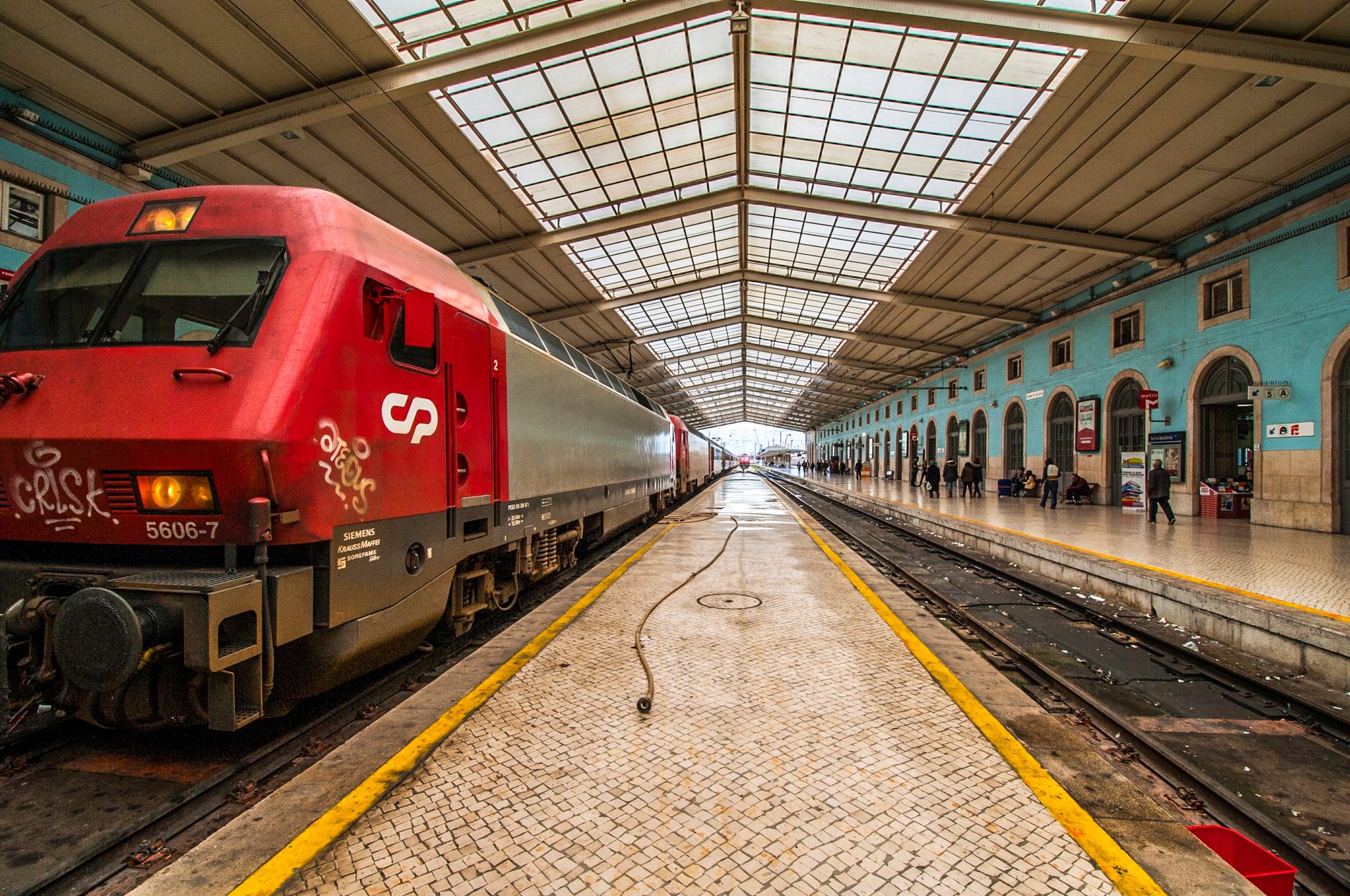 Vibrant red train at Lisbon's ornately designed Rossio Railway Station platform.