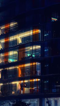 A modern office building glowing at night with bright interior lights in Barcelona, Spain.