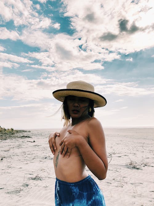 站在海灘上的棕色帽子的裸照女人