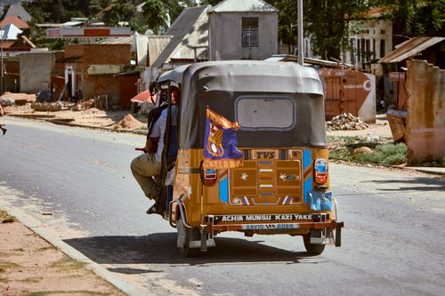 Free A bright tuk-tuk navigates a bustling urban road in a sunny locale. Stock Photo