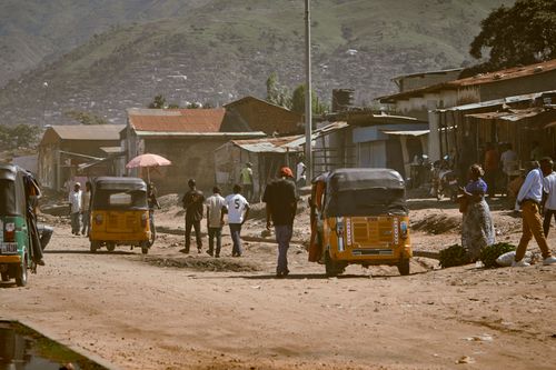Free Street view with rickshaws and locals against a scenic mountain backdrop. Stock Photo
