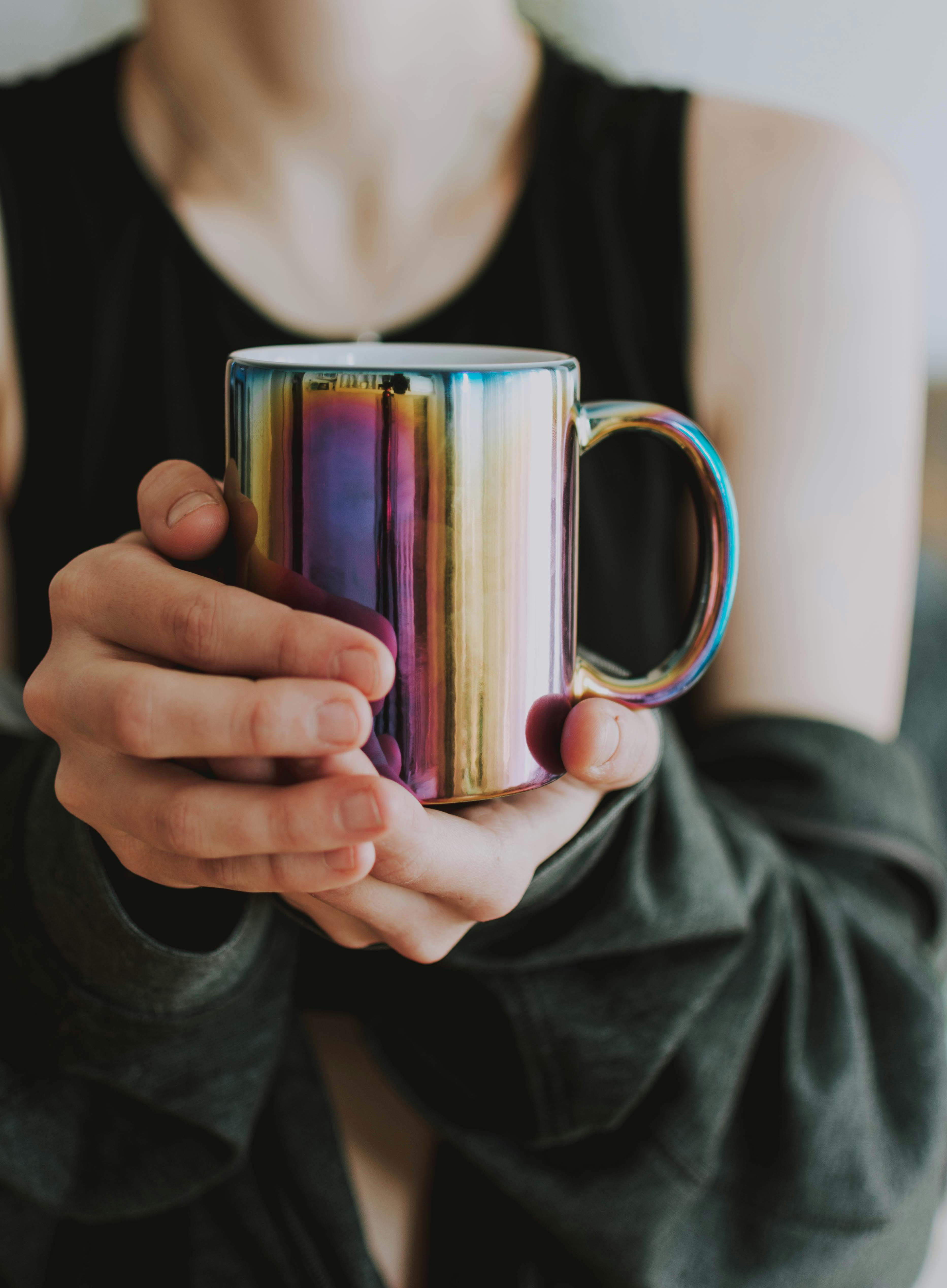 person holding purple and gold mug