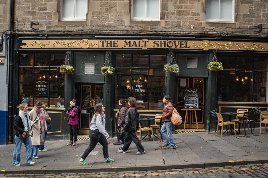 Street scene with people walking past 'The Malt Shovel' pub in Edinburgh, Scotland.