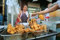 A vibrant scene of a Filipino street vendor in Manila preparing local fried snacks.
