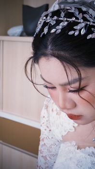 Close-up of a beautiful Vietnamese bride with a delicate lace dress and an elegant headpiece, capturing a serene moment.