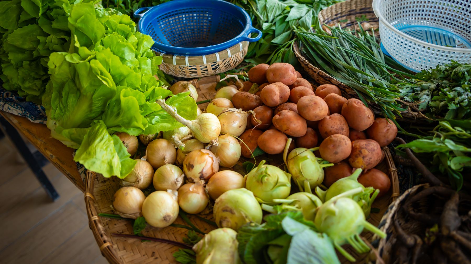 Colorful assortment of fresh vegetables including lettuce, potatoes, and onions on a market table.