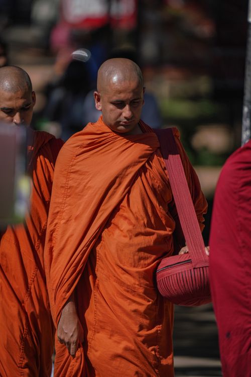 Free Buddhist monks in orange robes walk in a spiritual procession outdoors, symbolizing faith and tradition. Stock Photo