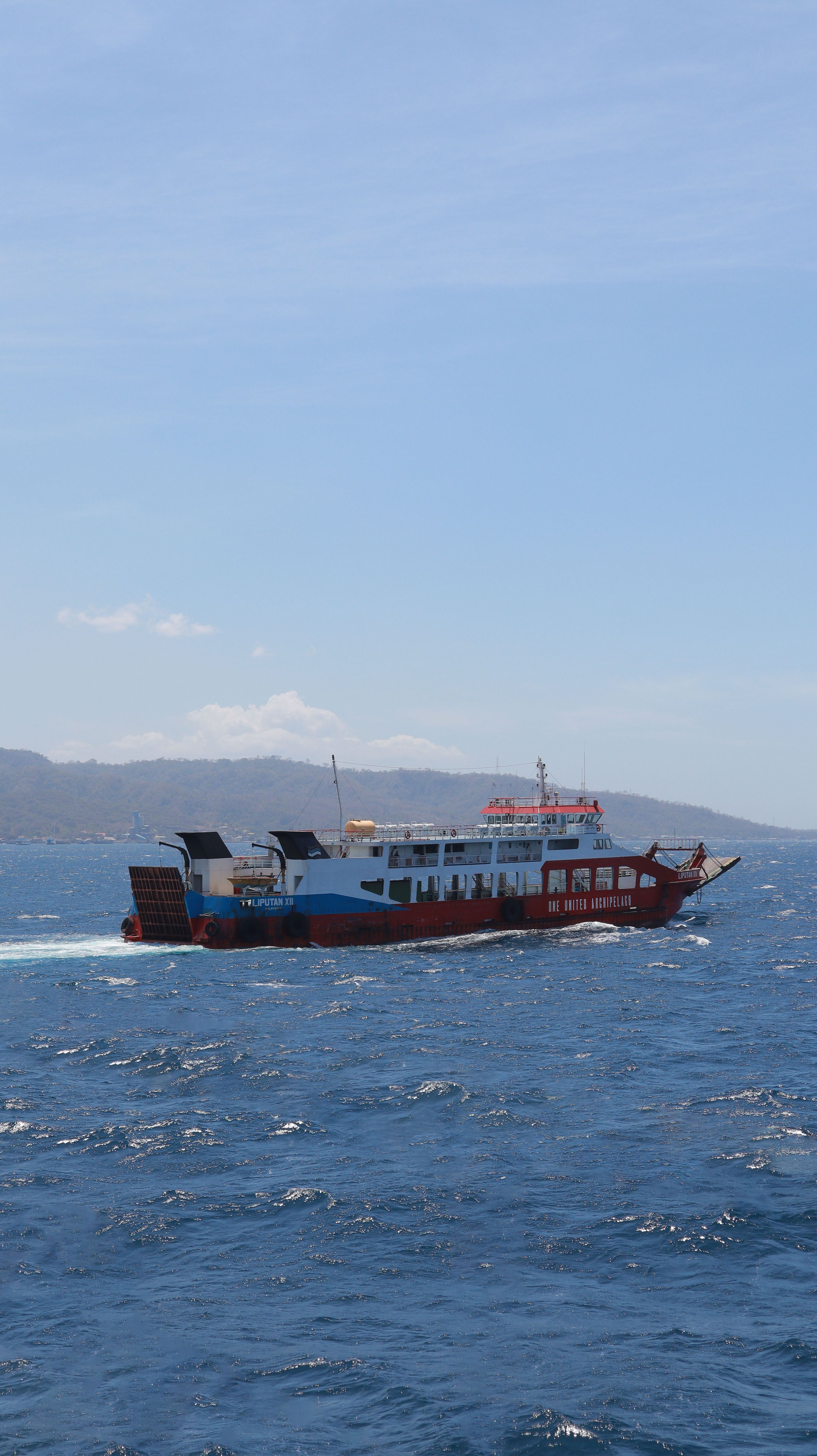 A vibrant passenger ferry sails through the blue waters of Indonesia, showcasing marine travel.