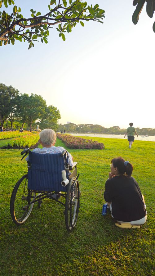 Free Elderly person and caregiver enjoy a serene afternoon by the river in Bangkok. Stock Photo