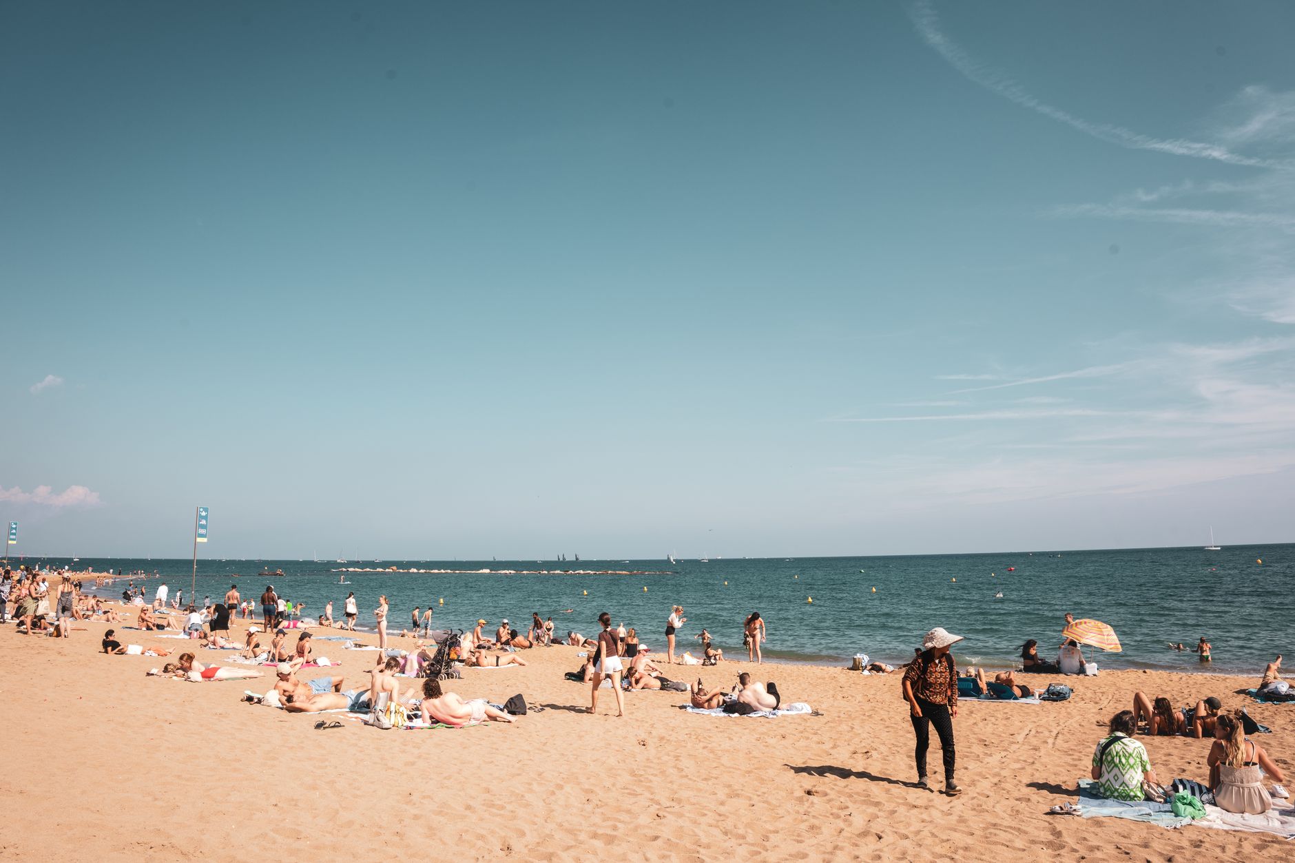 A vibrant sunny day at a Barcelona beach with people enjoying the sand and sea under a clear sky.