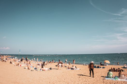 A vibrant sunny day at a Barcelona beach with people enjoying the sand and sea under a clear sky.