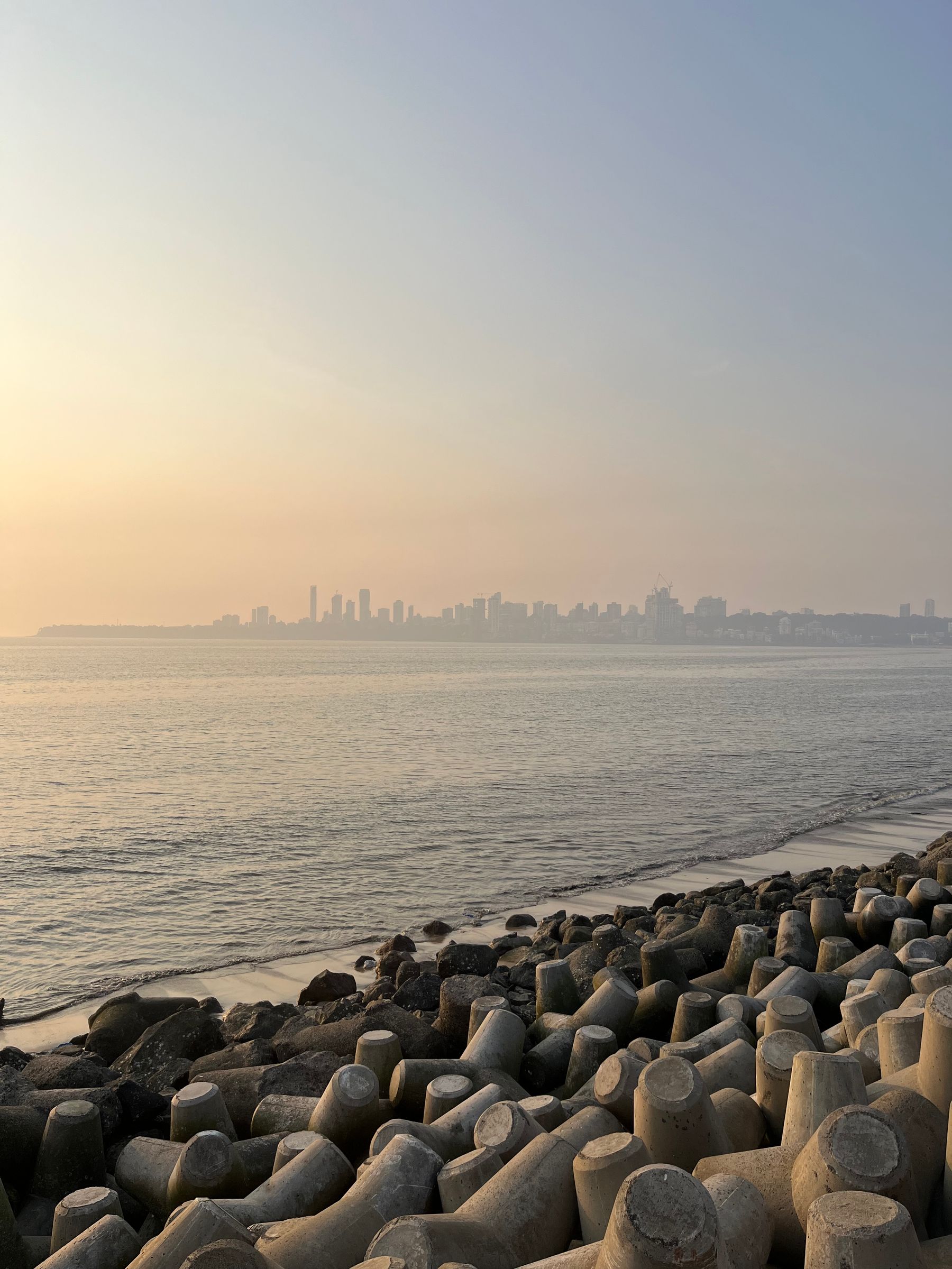 Tetrapods on the shore, Mumbai skyline at sunset