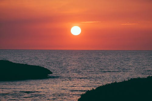 日落期间海上岩石形成的剪影