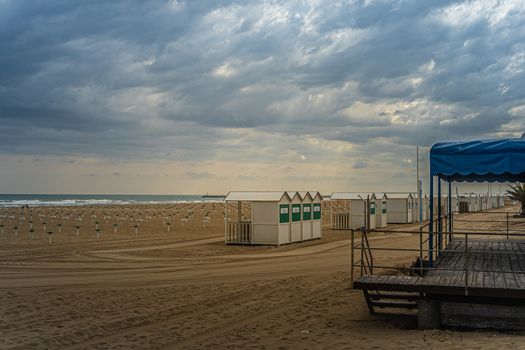 A quiet beachfront scene with beach huts and cloudy sky, conveying a serene and undisturbed atmosphere.