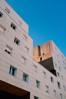 Low angle view of a modern apartment building with a blue sky backdrop, showcasing architectural elegance.