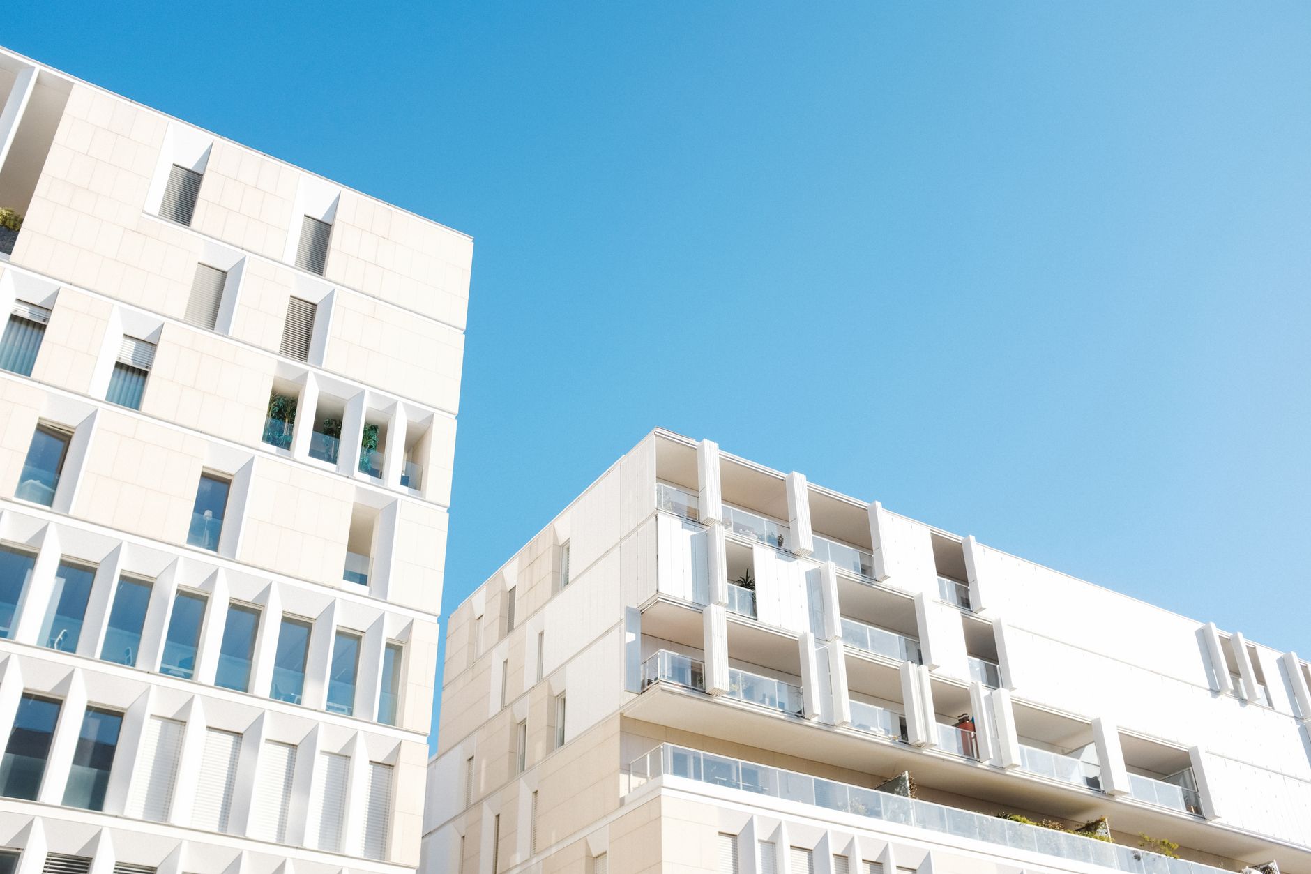 Low-angle view of a modern apartment building with a clear blue sky, highlighting clean, minimalist design.