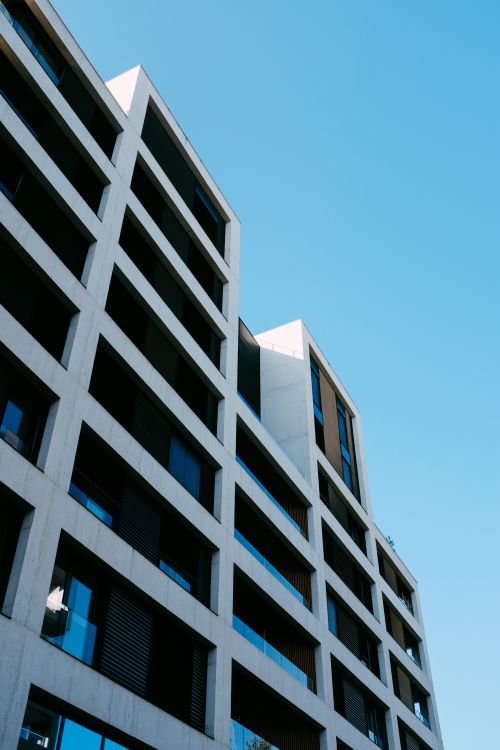 Free Low angle view of a modern, minimalist office building with a blue sky background, showcasing architectural design. Stock Photo