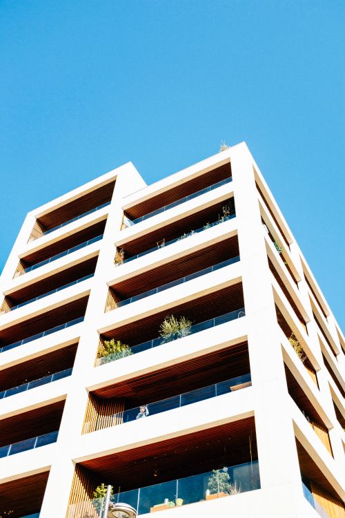 Free Low angle shot of a modern architectural building with a clear blue sky backdrop, showcasing minimalist design. Stock Photo