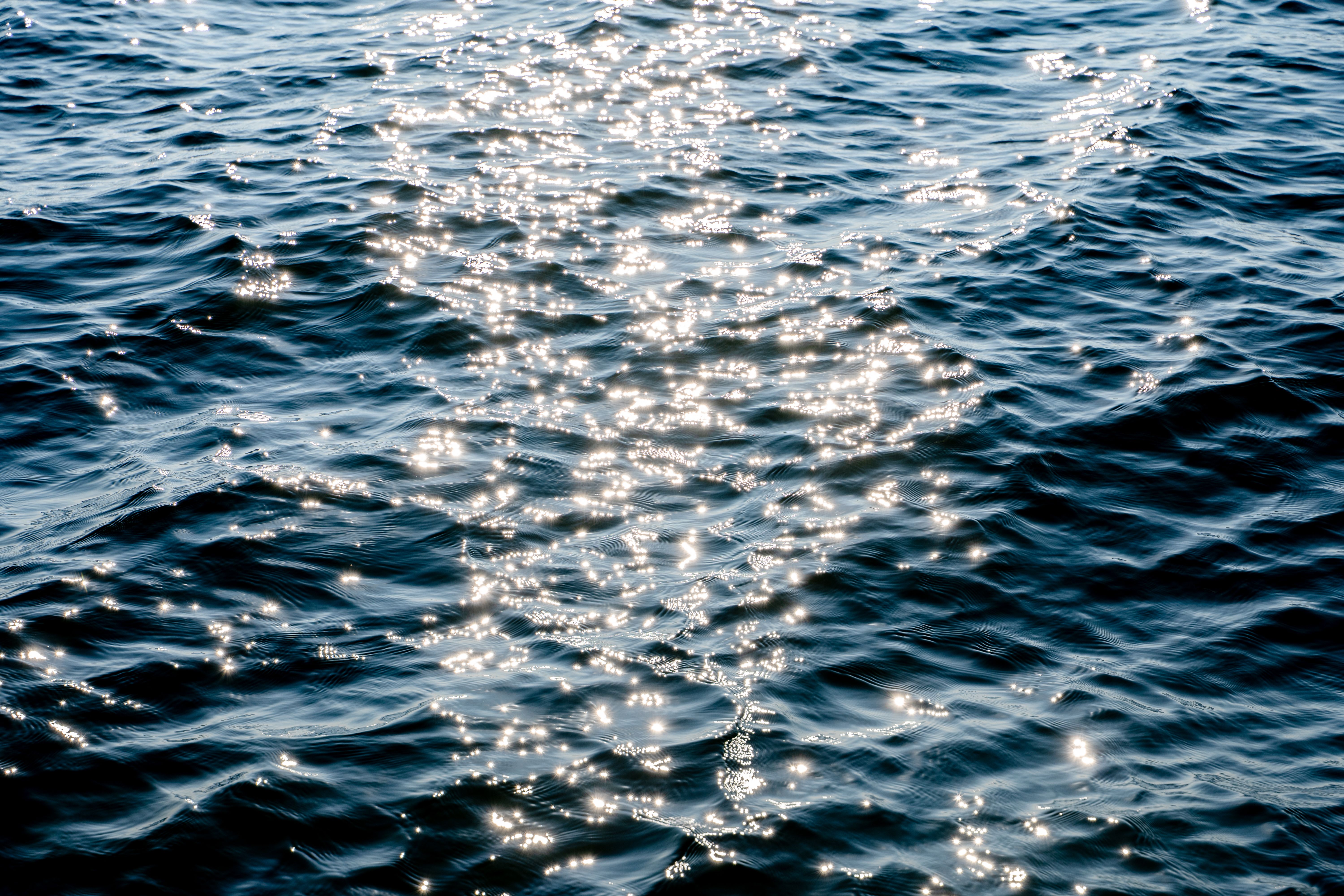 A serene view of sunlight reflecting off blue ocean waves creating a sparkling effect.